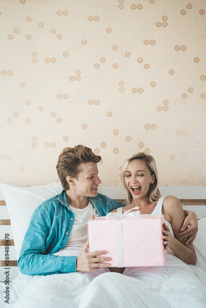 Boyfriend surprise his girlfriend with gift box on the bed Boyfriend surprise his girlfriend with gift box on the bed