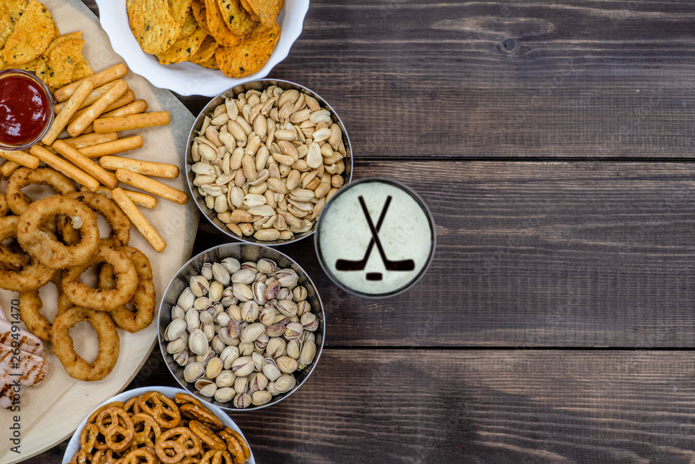 Mix of snacks and beer with silhouettes of hockey sticks on beer foam. Top view, Empty space for text Mix of snacks and beer with silhouettes of hockey sticks on beer foam. Top view, Empty space for text