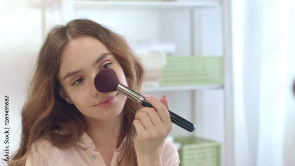 Sensual woman applying powder by cosmetic brush while morning makeup in bathroom Sensual woman applying powder by cosmetic brush while morning makeup in bathroom