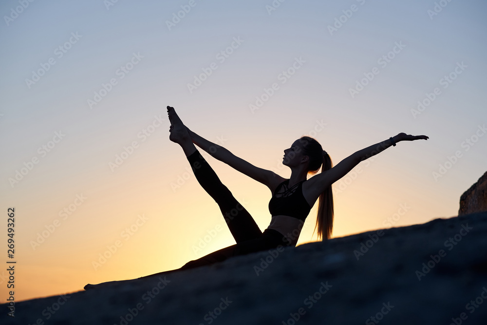 Silhouette woman practicing yoga or stretching at sunset or sunrise