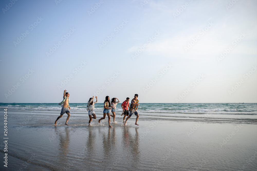 A group of male and female friends who play fun on the white sand beach amid the blue sky.