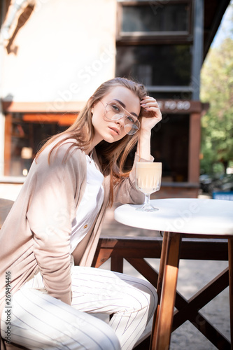 beautiful blond girl near the cafe with a cup of coffee