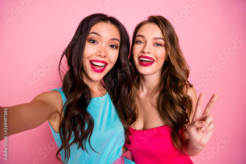 Close up photo two beautiful she her ladies graduation coquettish adorable showing v-sign say hi instagram followers wear pretty shiny colorful dresses formal-wear isolated pink rose vivid background