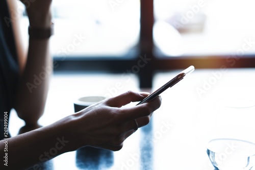 Close up of women s hands holding smartphone  female using mobile phone during coffee break.