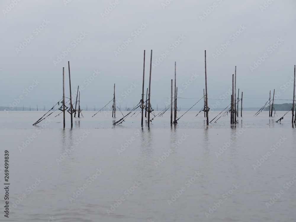 Bamboo poles adhered to the net for catch fish reflection in the water sea environmet background Bamboo poles adhered to the net for catch fish reflection in the water sea environmet background