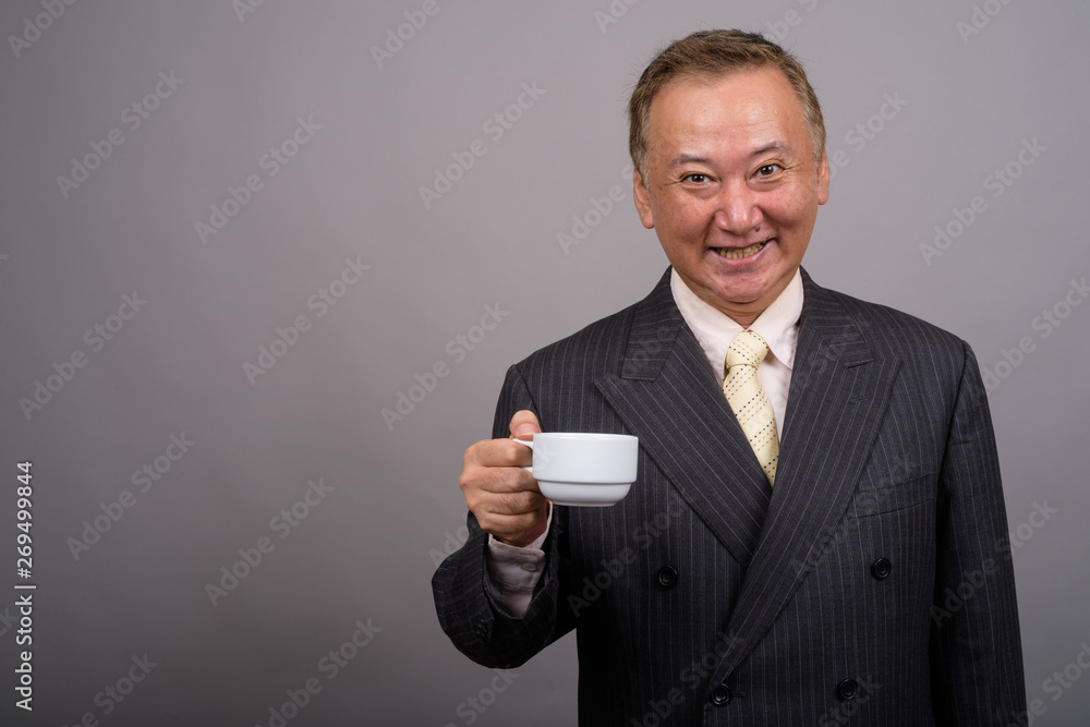 Portrait of mature Asian businessman against gray background Portrait of mature Asian businessman against gray background