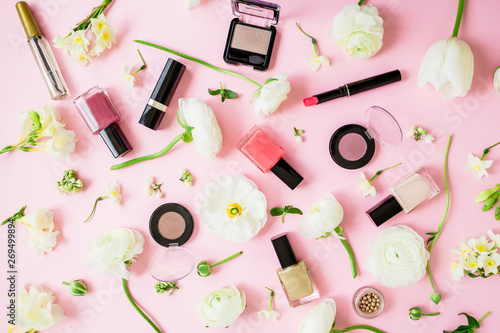 Feminine cosmetics and white flowers on pink background. Flat lay, top view. Beauty concept for woman with lipstick, nail polish