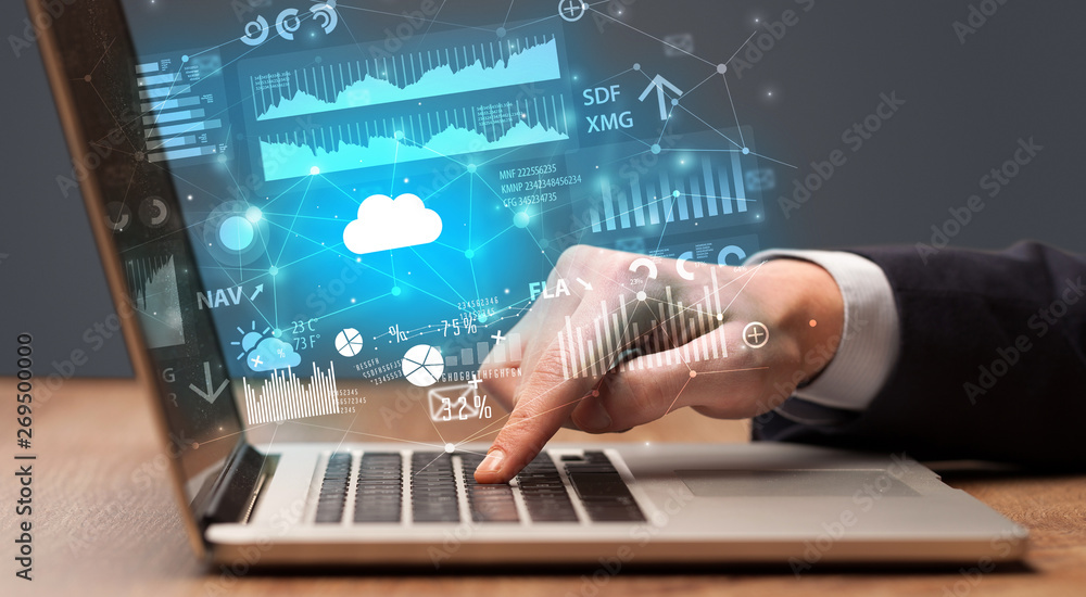 Businessman hand typing on laptop with reports and graphs concept around
