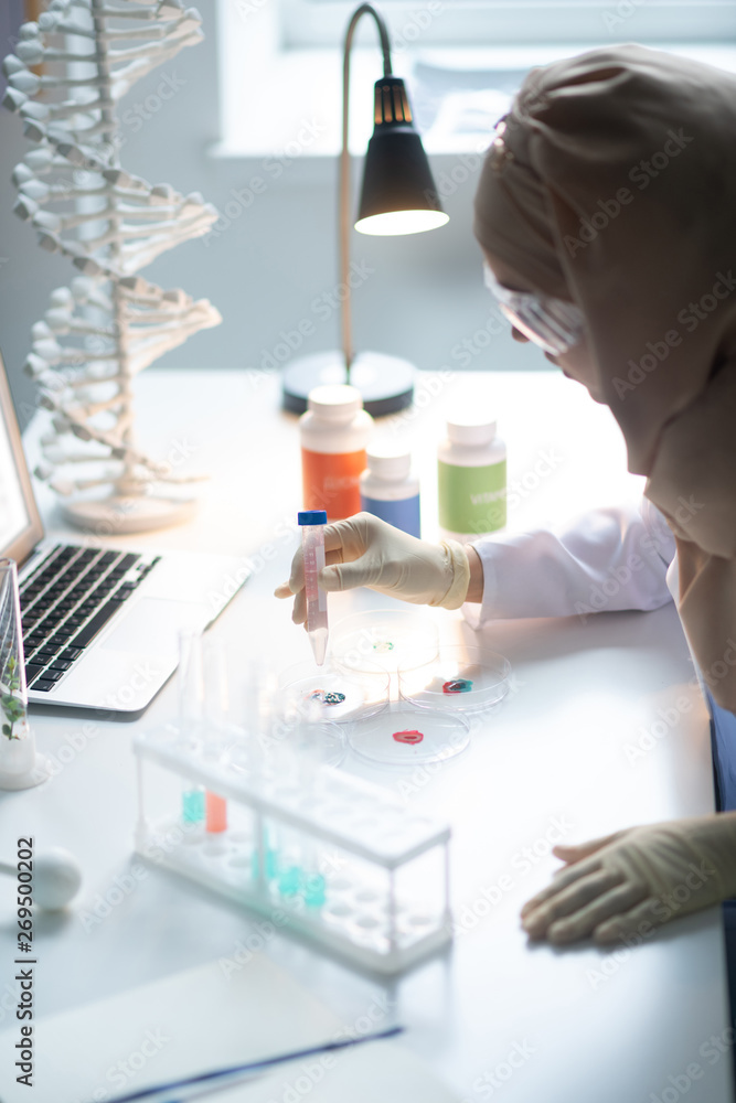 Chemist sitting at table with lamp and studying chemical agents Chemist sitting at table with lamp and studying chemical agents