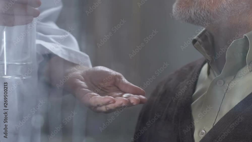 Aged man taking pills from doctors hand, properly care in retirement home Aged man taking pills from doctors hand, properly care in retirement home