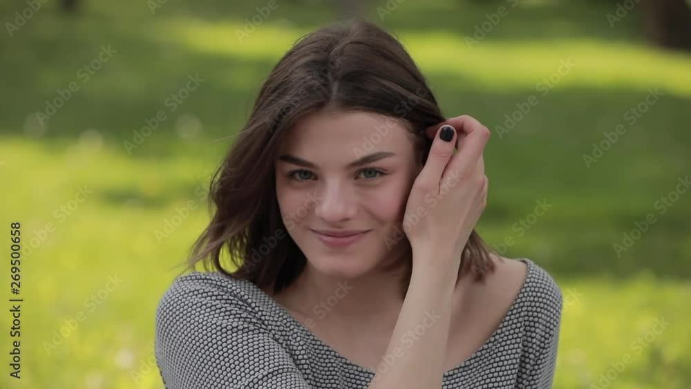 Portrait of smiling happy young woman sitting in the park tossing hair Portrait of smiling happy young woman sitting in the park tossing hair