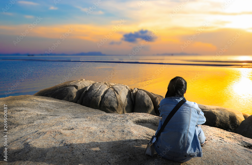 Lonely girl sitting on the rock looking the sunset Lonely girl sitting on the rock looking the sunset