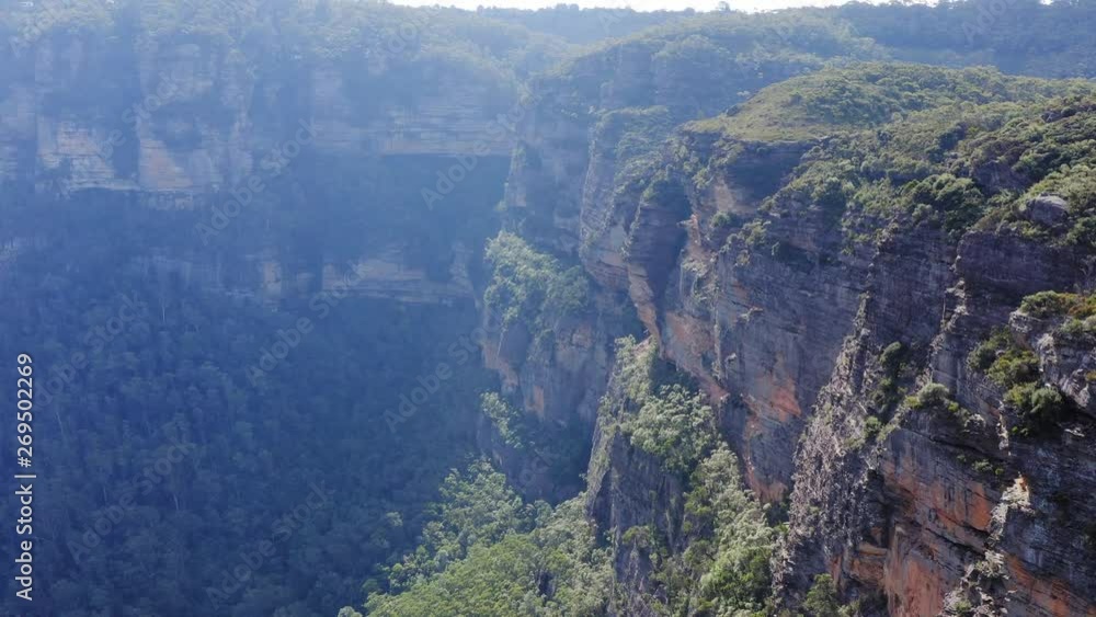 Flying close along a cliff line in the mountains - aerial footage flying towards the sun Flying close along a cliff line in the mountains - aerial footage flying towards the sun