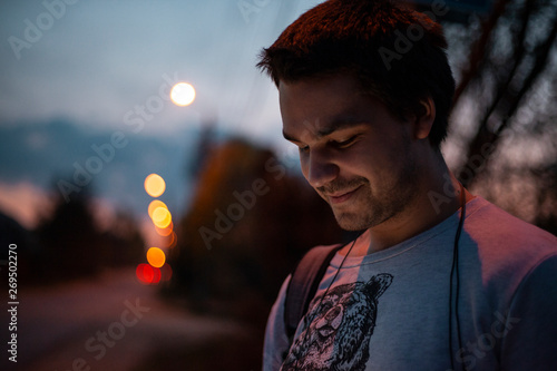 A man looks at the phone in the evening against the road