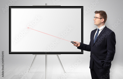 Young businessman with laser pointer and copyspace white wall 