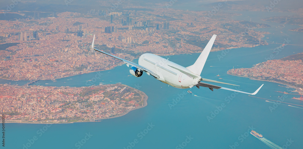 A passenger airplane is flying over istanbul city with blue sea A passenger airplane is flying over istanbul city with blue sea