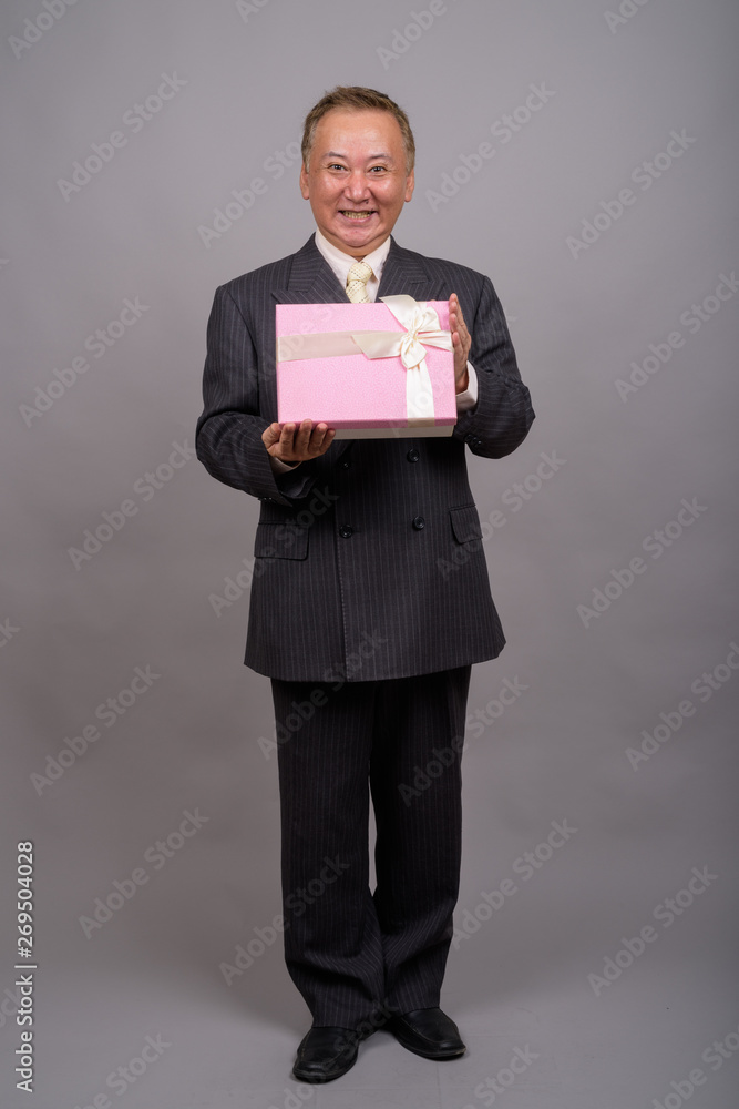 Portrait of mature Asian businessman against gray background Portrait of mature Asian businessman against gray background