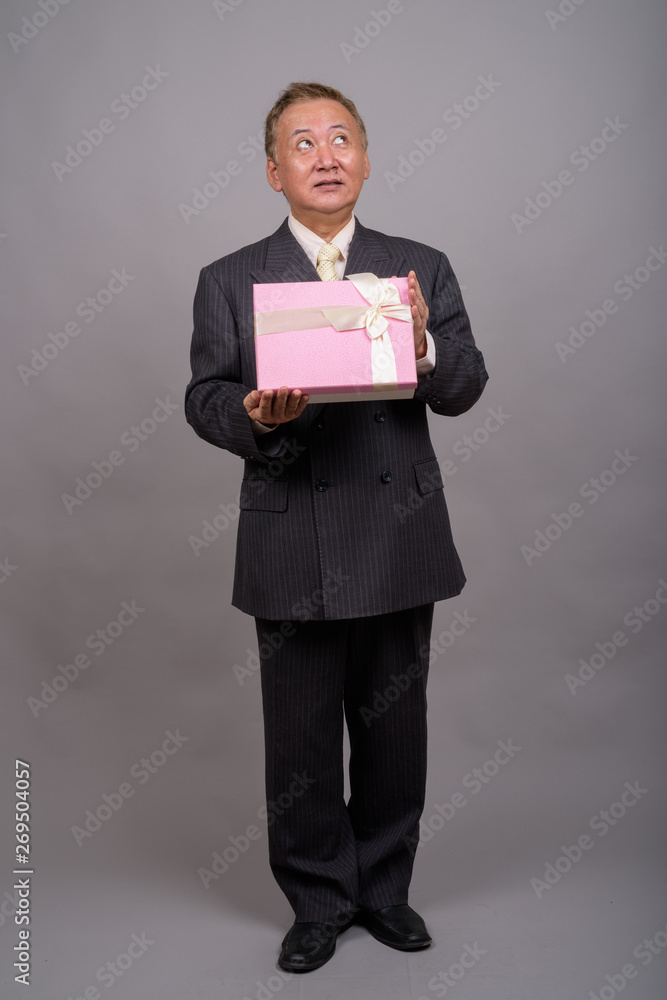 Portrait of mature Asian businessman against gray background Portrait of mature Asian businessman against gray background