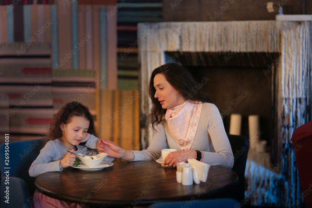 mother and daughter eat ice cream in dark cafe mother and daughter eat ice cream in dark cafe