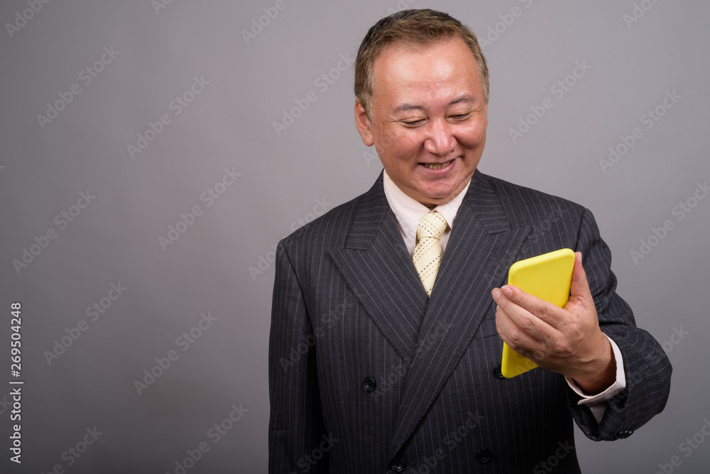 Portrait of mature Asian businessman against gray background Portrait of mature Asian businessman against gray background