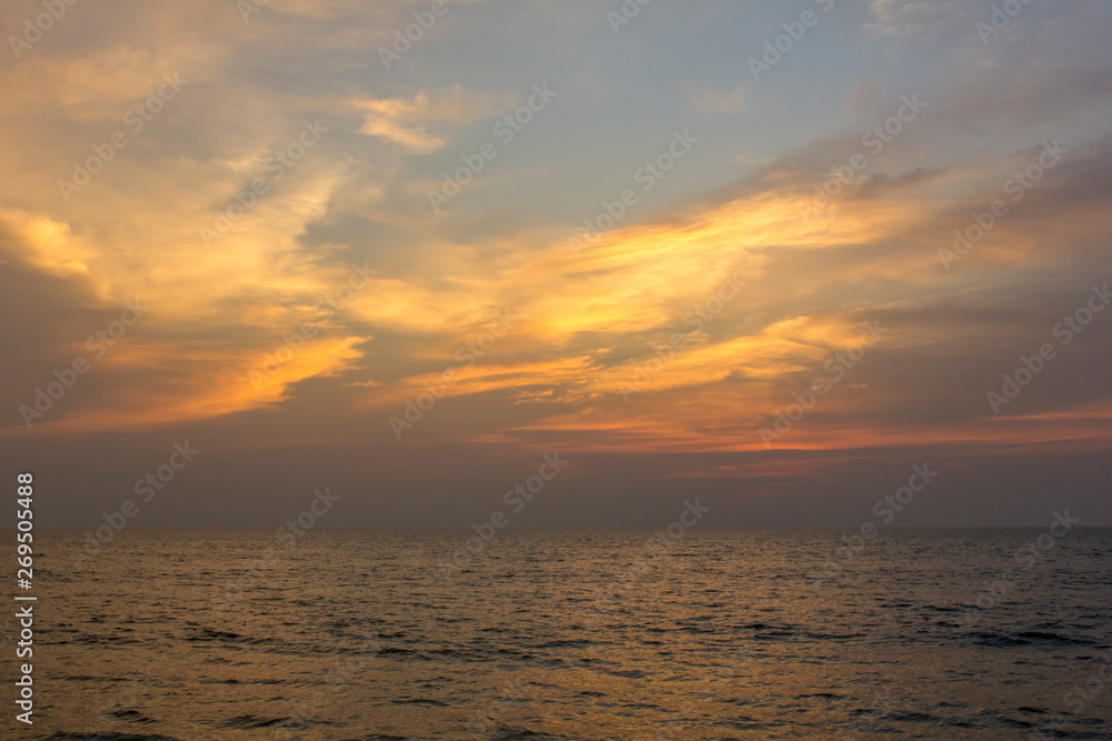 ocean under purple sunset sky with bright orange clouds