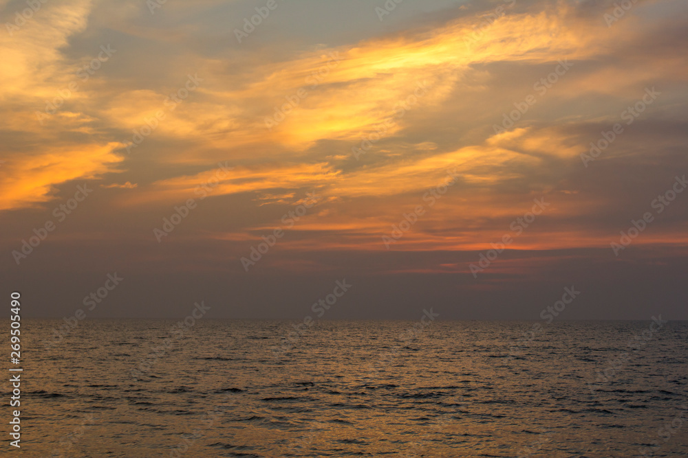 Obraz premium sea under a purple sunset sky with bright orange clouds