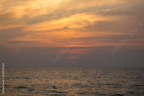 ocean under a purple sunset sky with bright yellow clouds