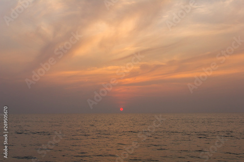 ocean against a purple sunset sky with bright red sun