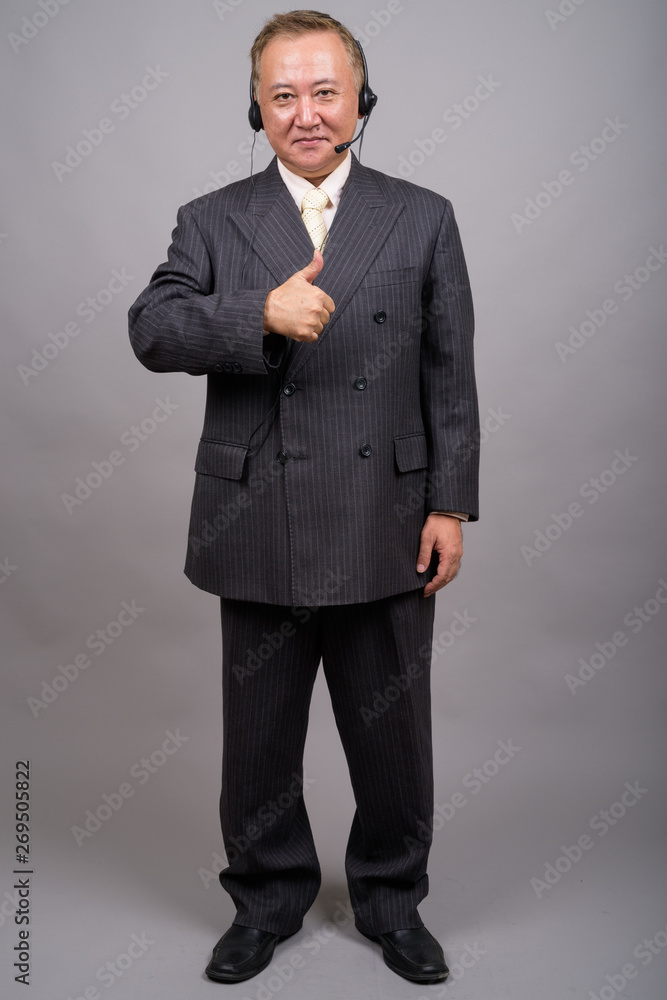 Portrait of mature Asian businessman against gray background Portrait of mature Asian businessman against gray background