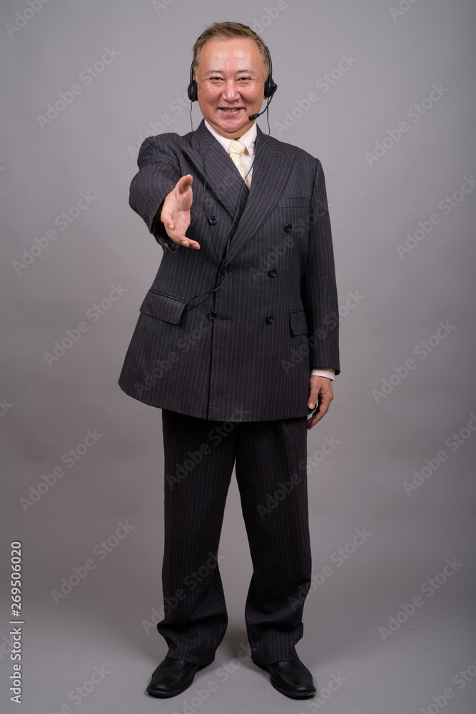 Portrait of mature Asian businessman against gray background Portrait of mature Asian businessman against gray background