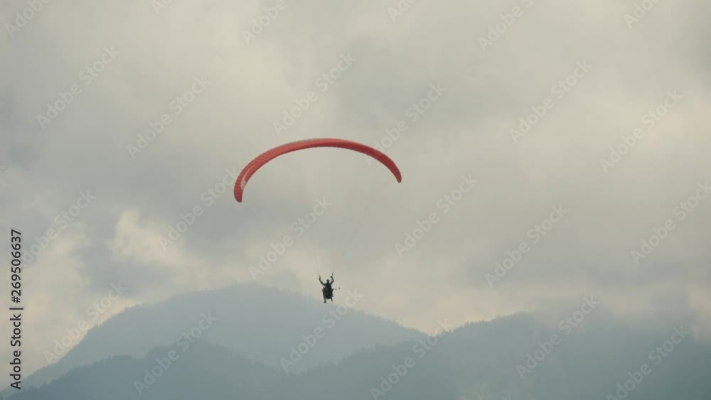 The paraglider flies in the clouds over the mountains on a cloudy day. Extreme sport. Lifestyle. Adrenaline. The paraglider flies in the clouds over the mountains on a cloudy day. Extreme sport. Lifestyle. Adrenaline.
