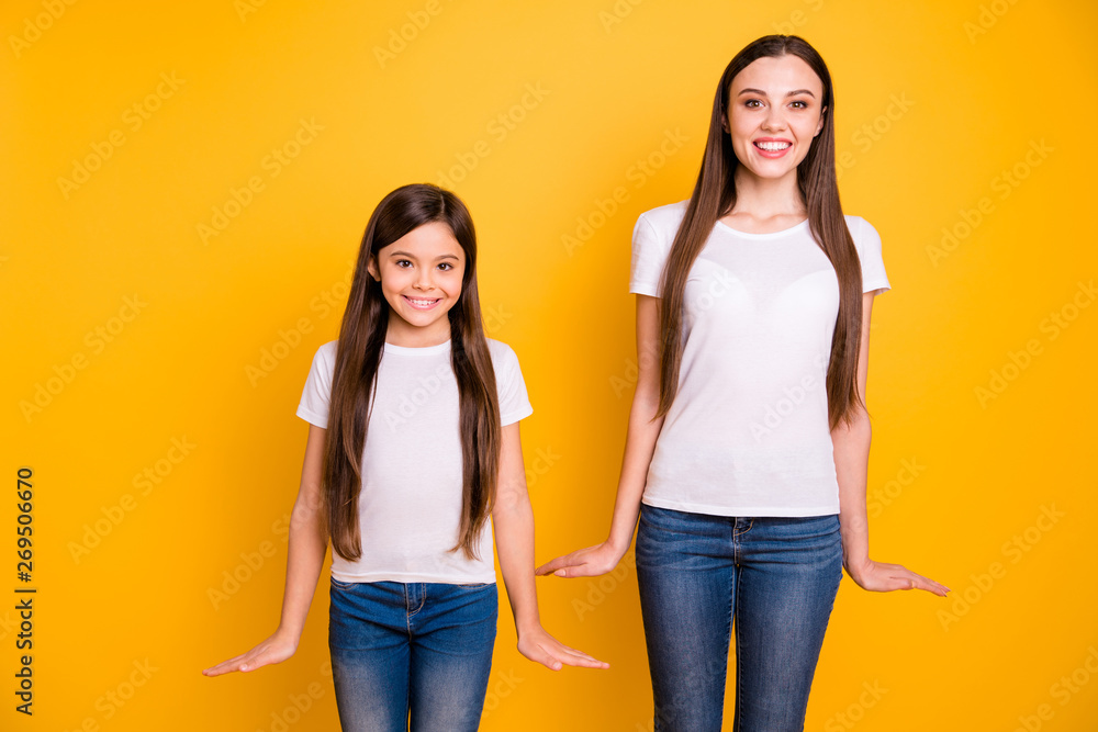 Close up photo two beautiful her she diversity lady different age buddies hold hands arms sides attractive appearance wear casual white t-shirts jeans denim clothes isolated yellow bright background - obrazy, fototapety, plakaty 