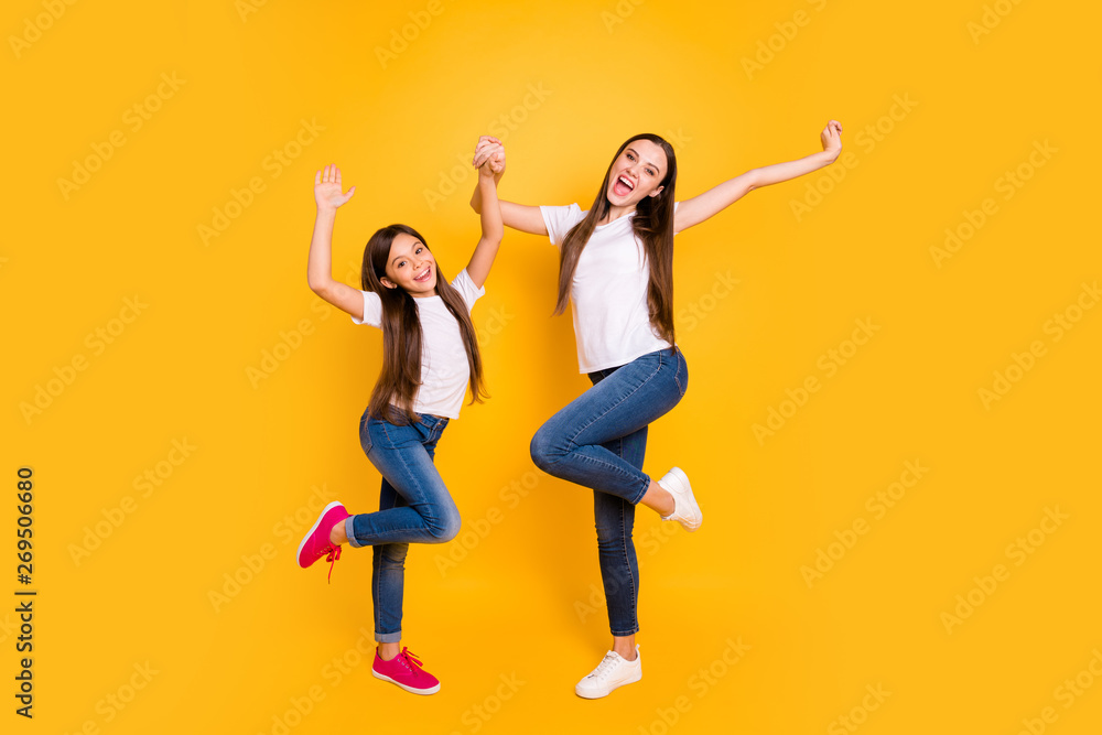 Full length body size photo two beautiful her she diversity lady different age hands arms raised up scream shout yell yeah wear casual white t-shirts jeans denim isolated yellow bright background