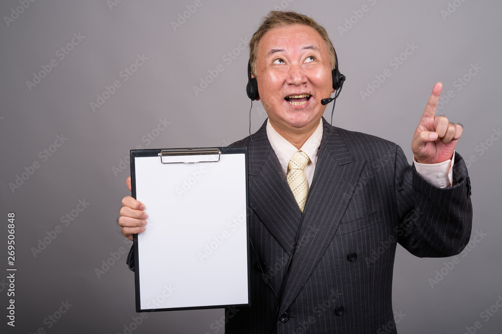 Portrait of mature Asian businessman against gray background