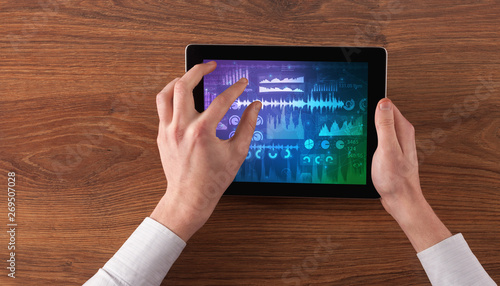 Hand touching tablet with waveforms and sound design concept
