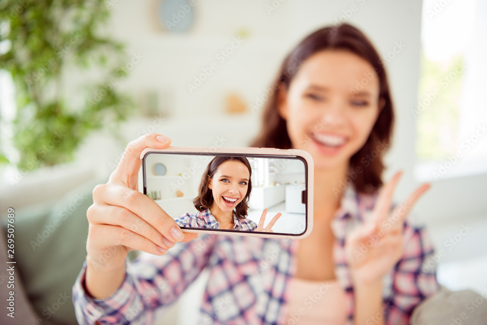 Close up photo of positive cheerful content lady excited millennial make v-signs video call live photos blog blogger good-looking joy style hair wavy curly checked shirt clothing cotton room