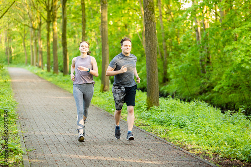 young woman and man running in a forest and making fitness