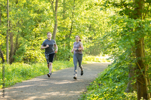young woman and man running in a forest and making fitness