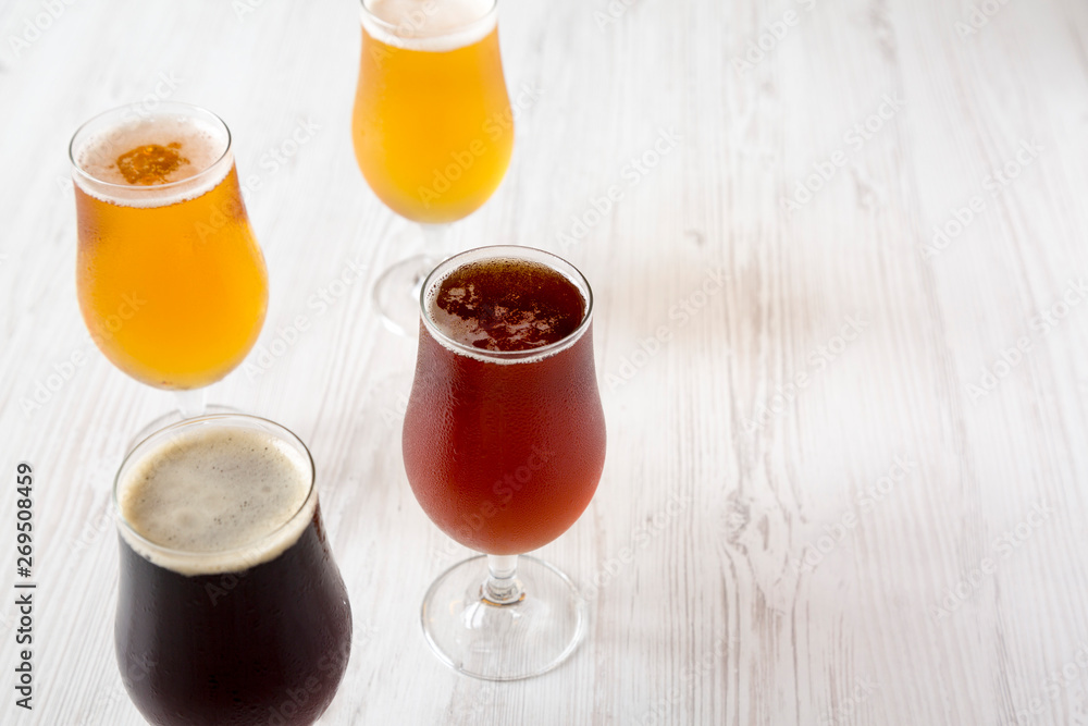 Assorted cold craft beer on a white wooden background, side view. Copy space.