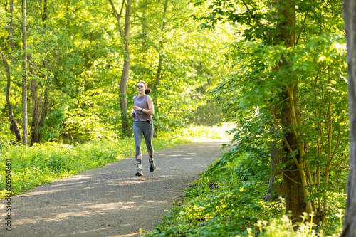 young woman running in a forest and makes fitness
