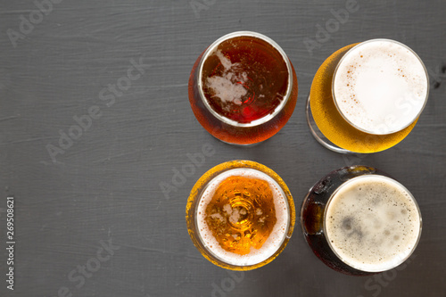 Assorted beers on a black surface, top view. Overhead, from above. Copy space.