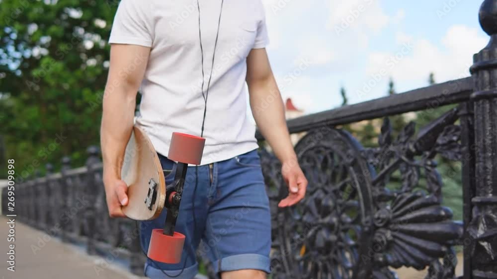 Close up of young man holding longboard deck in hands on a summer day Close up of young man holding longboard deck in hands on a summer day