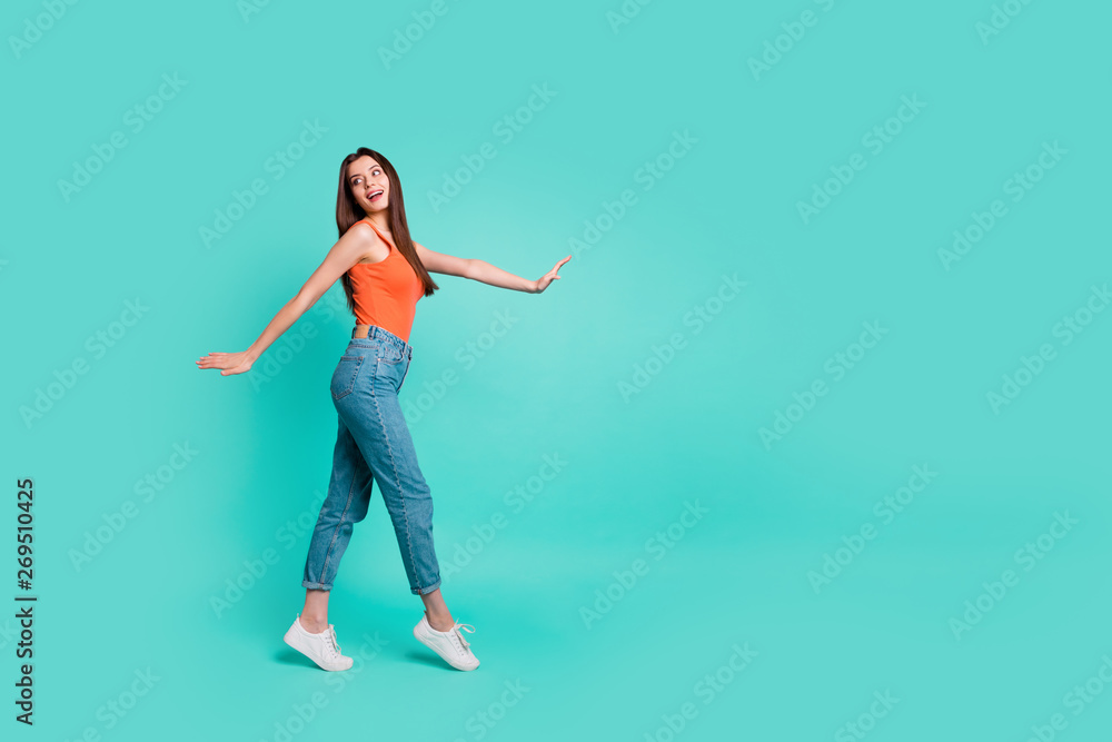 Full length side profile body size photo beautiful her she lady wondered look empty space easy-going weekend walking park wear orange tank-top jeans denim isolated bright teal turquoise background