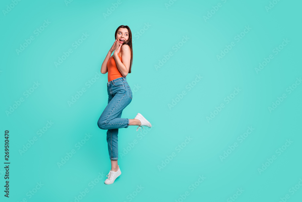 Full length side profile body size photo beautiful her she lady wondered sincere easy-going weekend mood excited wear casual orange tank-top jeans denim isolated bright teal turquoise background Full length side profile body size photo beautiful her she lady wondered sincere easy-going weekend mood excited wear casual orange tank-top jeans denim isolated bright teal turquoise background