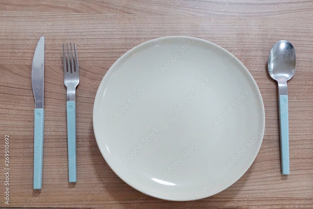 Top view of empty plate with fork, spoon and knife on wooden table in restaurant Top view of empty plate with fork, spoon and knife on wooden table in restaurant