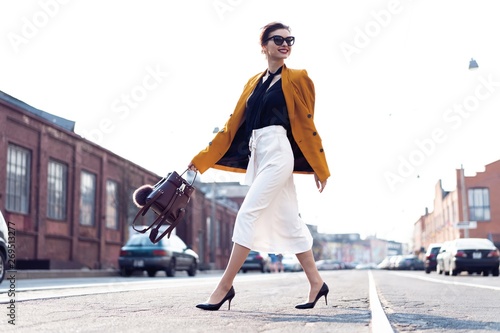 Happy young business woman walking on the street.