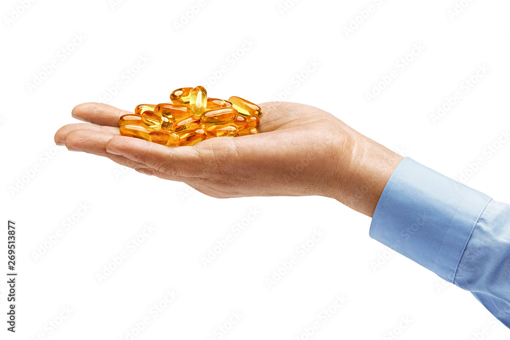Fototapeta premium Man's hand in shirt holds many capsules Omega 3 isolated on white background. Close up. High resolution product. Health care concept