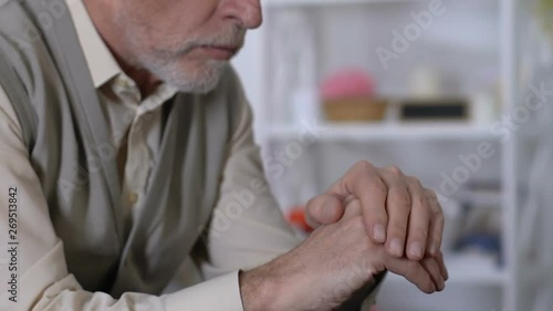 Old male looking at trembling hands in rehabilitation center, parkinsons disease photo