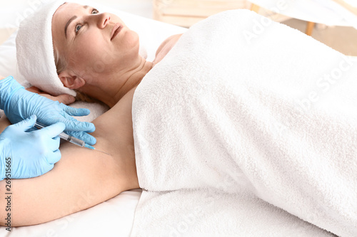 Woman receiving botox injection in armpit as treatment of hyperhidrosis in beauty salon