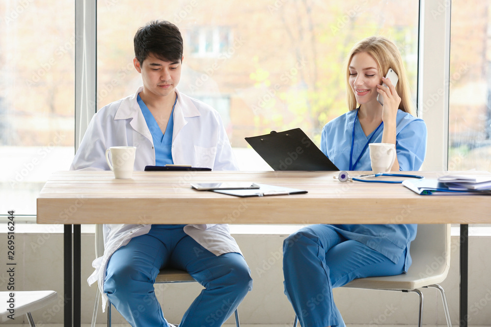 Male doctor and female medical assistant sitting at table in clinic Male doctor and female medical assistant sitting at table in clinic